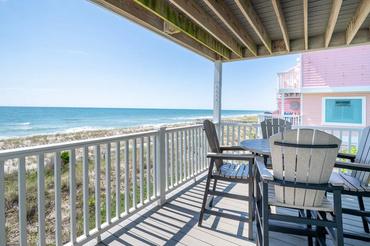 The image showcases a spacious oceanfront deck with comfortable seating overlooking the sparkling Atlantic, perfect for relaxing or dining outdoors. The serene setting features soft sunlight, a sturdy deck railing, and uninterrupted ocean views that stretch to the horizon, inviting guests to unwind and soak in the tranquil coastal atmosphere.