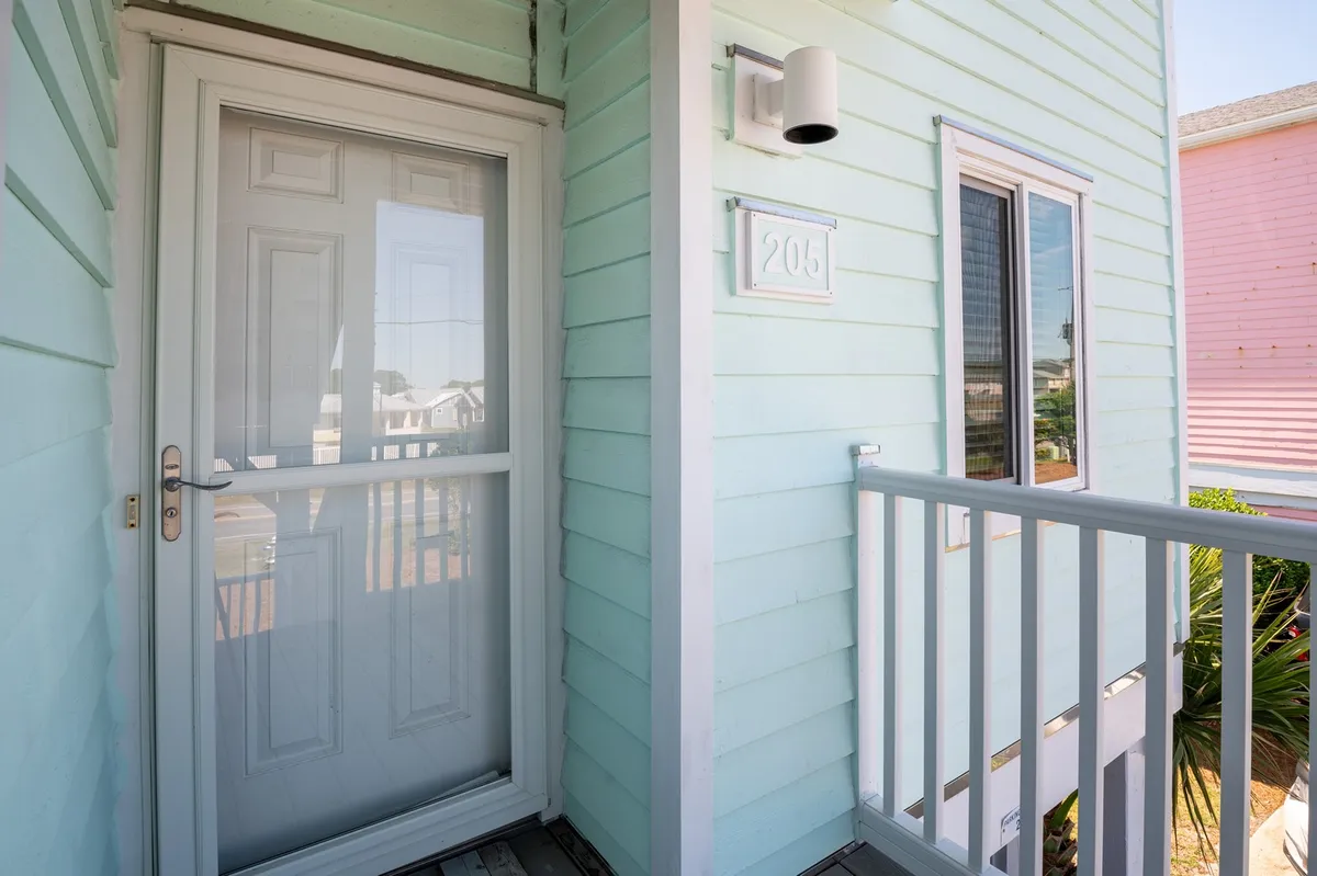 This image captures the home's front door, house number, balcony railing, and a window. The entrance is well-lit and inviting, giving a clear sense of the property's arrival point and exterior security.